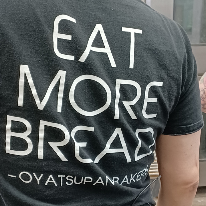 close up of person from back with t-shirt that reads eat more bread Oyatsupan Bakers