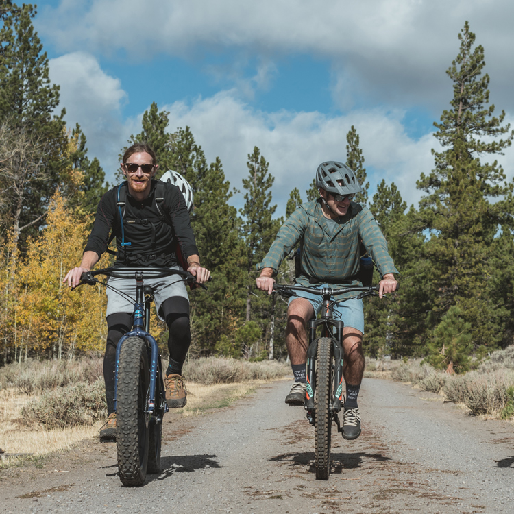 two cyclists riding towards the camera, one on fat bike, the other on mountain bike