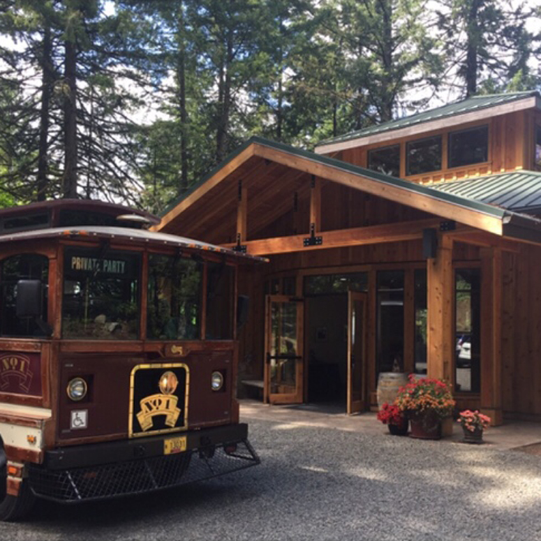 Trolley parked in front of wooden building with open doors.
