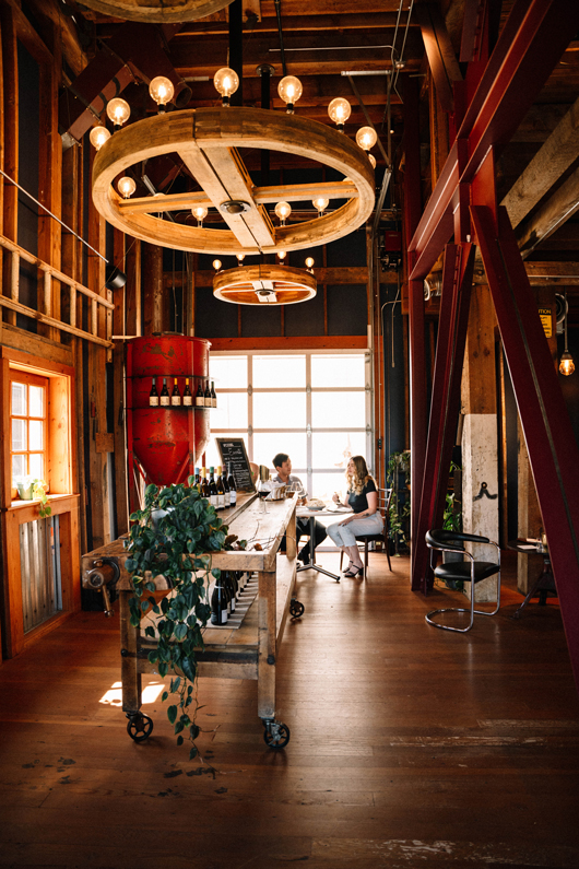 two people seated in a rustic and modern styled winery tasting room