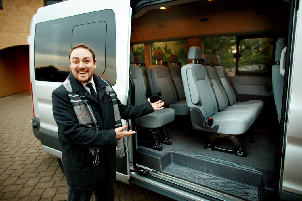 man stands next to open door of cargo van making welcoming gesture