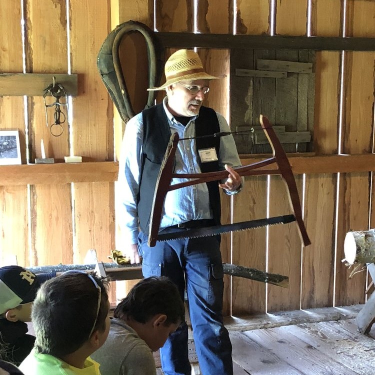 tour guide wearing straw hat holds old saw