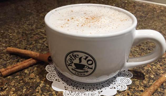 White coffee mug with cinnamon on marble countertop.