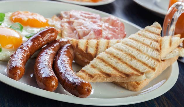 Breakfast plate with sausages, eggs, bacon, and toast.