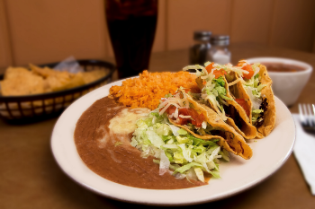 Plate with tacos, rice, beans, and salad.