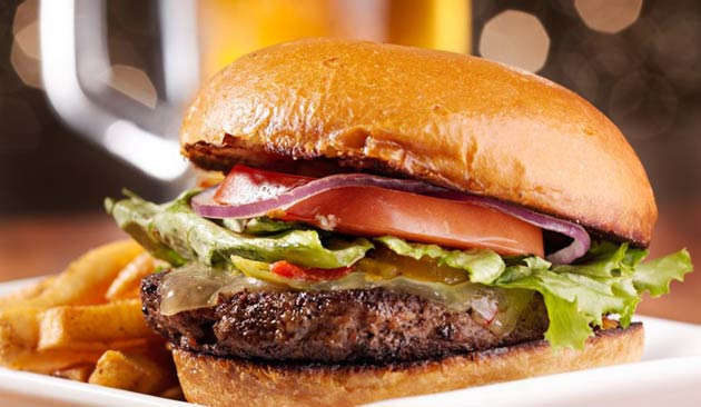 Burger with lettuce, tomato, and fries on a plate.