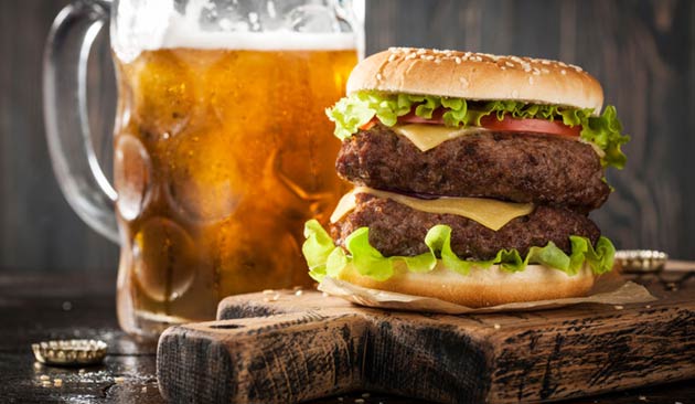 Double cheeseburger next to a mug of beer.