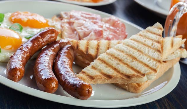 Breakfast plate with sausages, eggs, bacon, and toast.