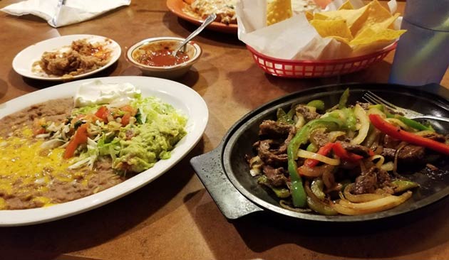 Mexican dishes: fajitas and beans with toppings.