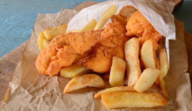 Fried fish and chips in a paper bag.
