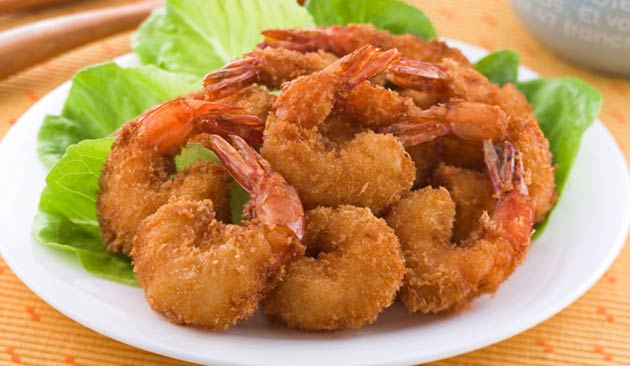 Fried shrimp on a white plate with lettuce.