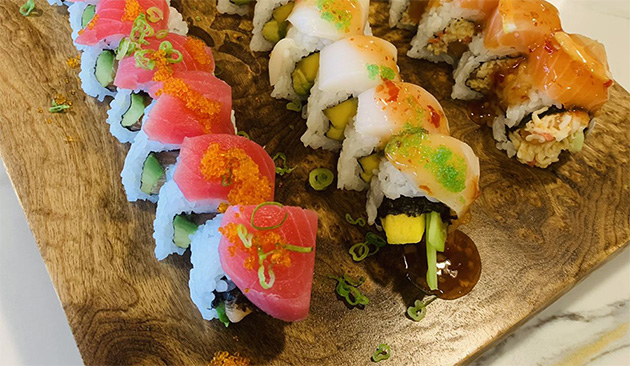three different sushi rolls on a wood board