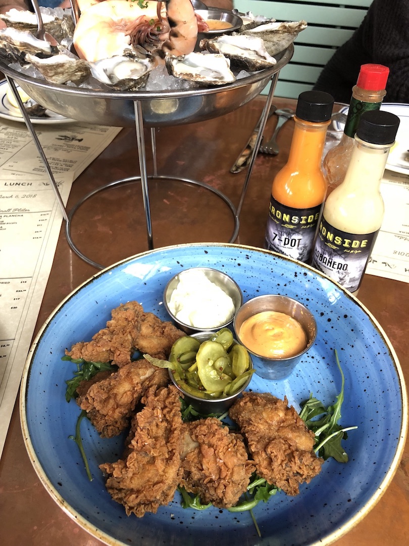 Fried chicken with dipping sauces and a tray of oysters.