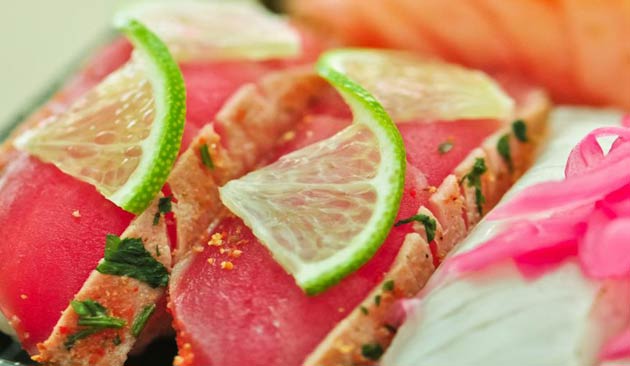 Sushi with lime slices and herbs.
