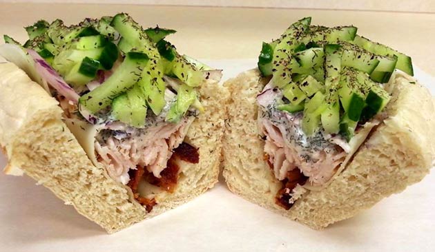 Two halves of a sandwich with turkey, cucumber, and red onions.