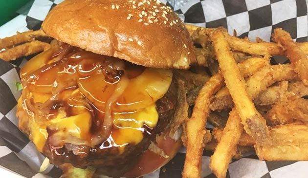 Burger with melted cheese, onions, and fries.