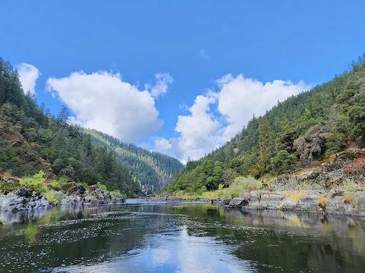 scenic rogue river under blue sky with fluffy clouds