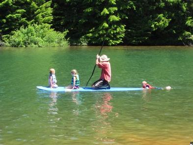 an adult and three children on paddle board