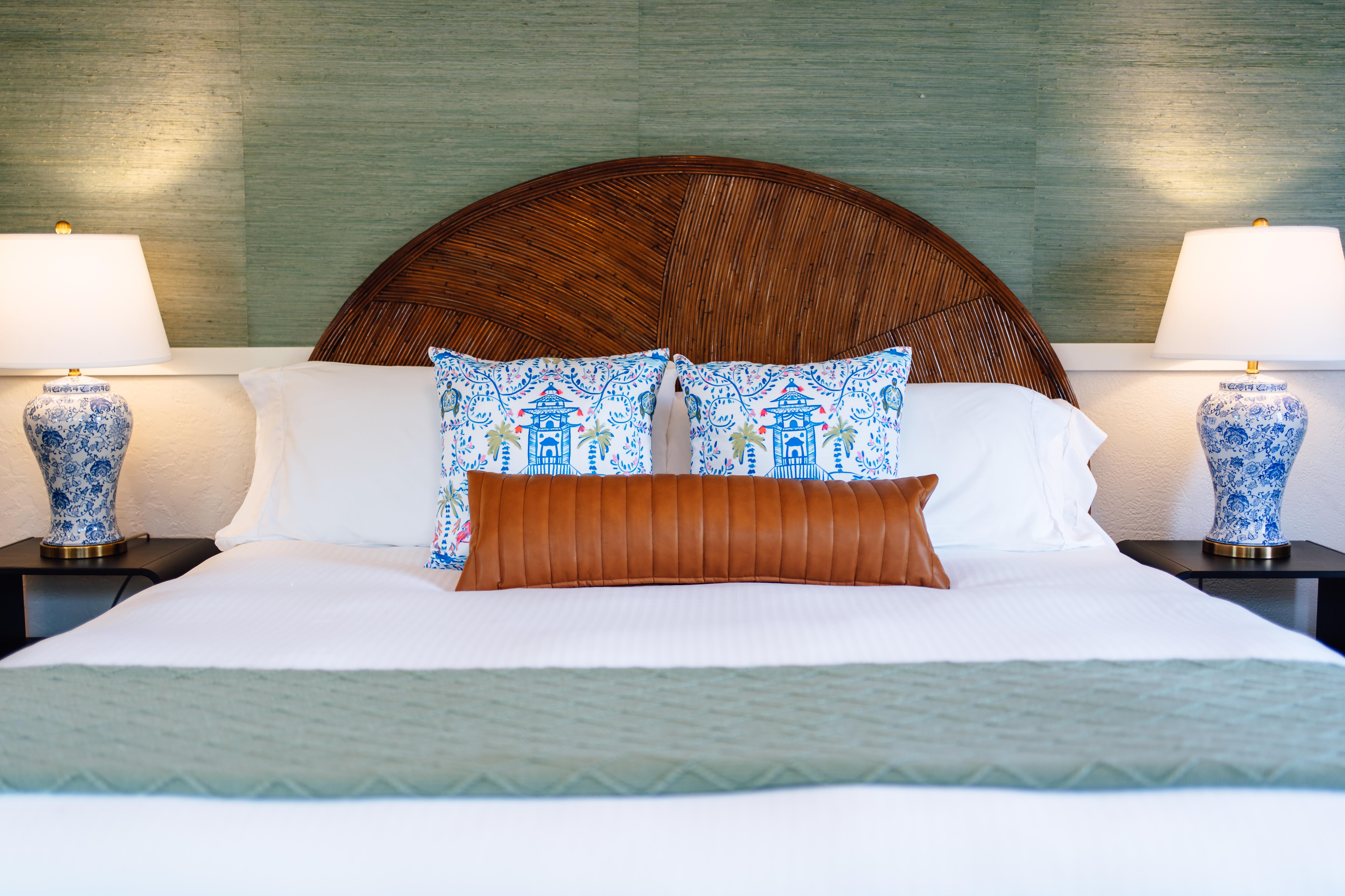 A neatly made bed with a curved wooden headboard.