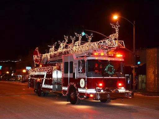 Firetruck decorated with holiday lights in a parade.