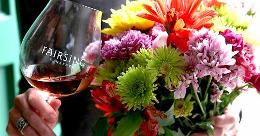 hand holding stemmed glass of red wine and a bouquet of flowers