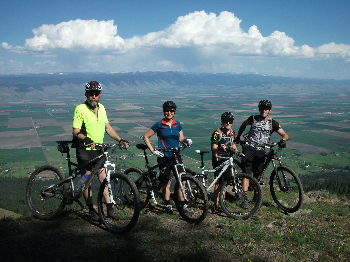 group of four bicyclists posing next their bikes with scenic view in background