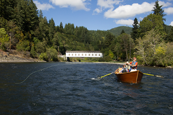 People in a small boat fly fishing on a river.