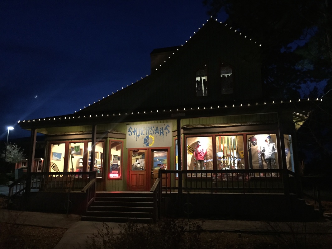 Store front with "Skyers's" sign and lit windows at night.