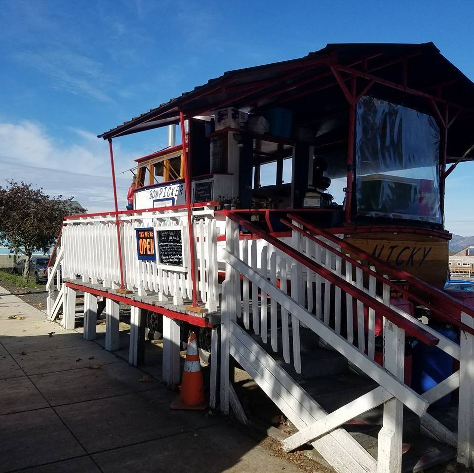 exterior of gillnet boat that has been converted into a restaurant with stairs leading up to a railed platform to order from
