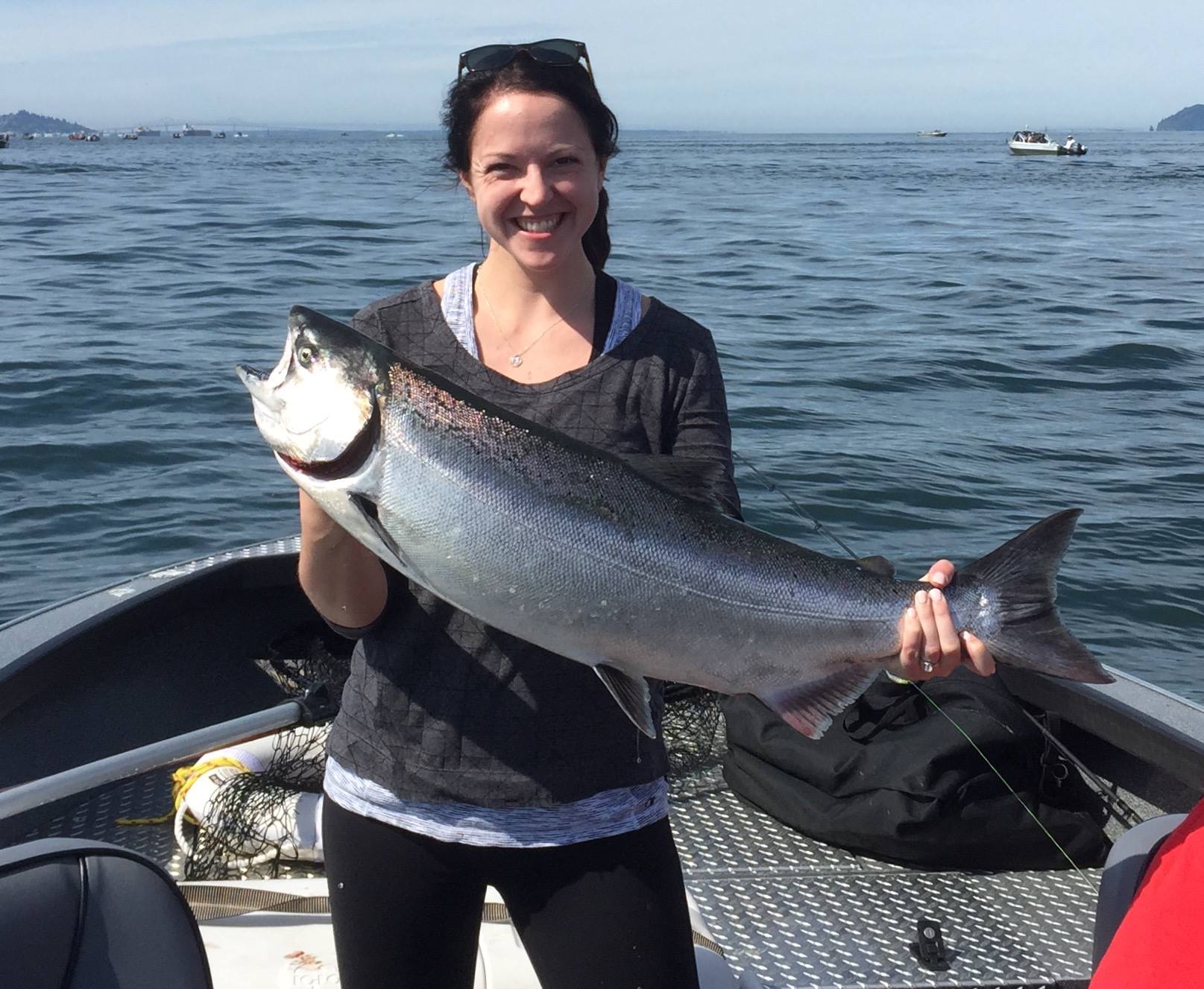 person standing in boat holding up freshly caught fish