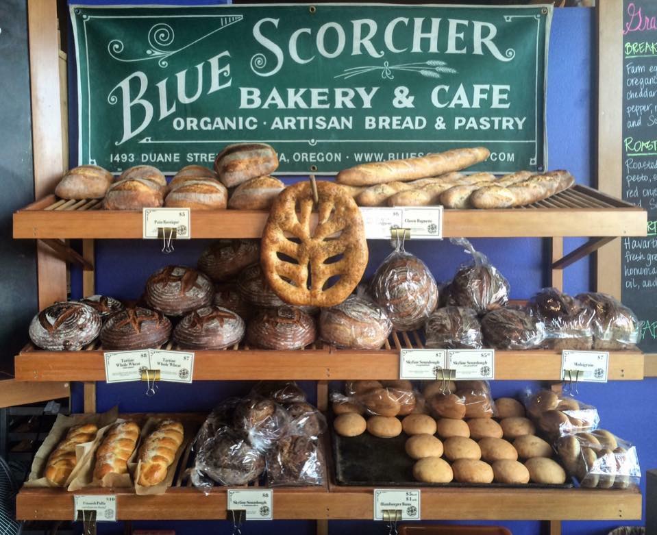 display of baked breads and rolls with sign for Blue Scorcher Bakery & Cafe at top of display