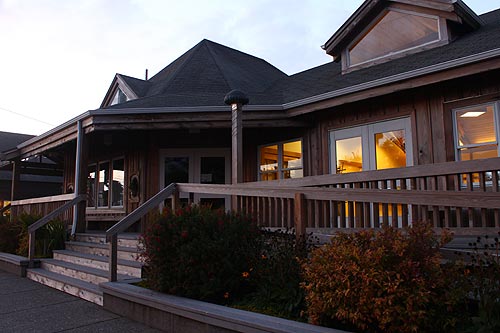 exterior of one story building with large windows and wrap around porch