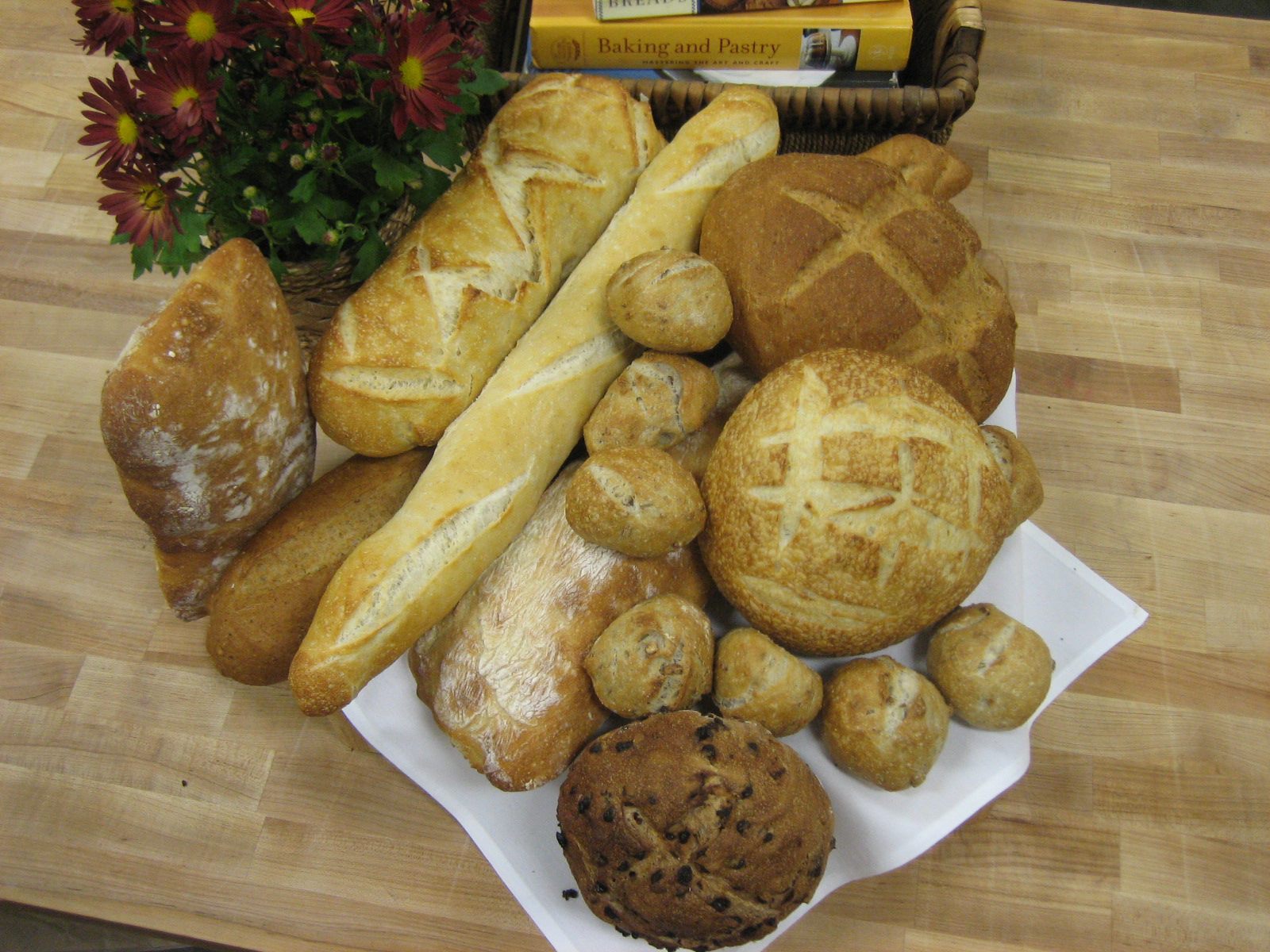 Various types of bread on a table with flowers.