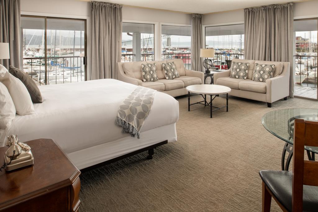 interior of hotel suite with sitting area and floor to ceiling windows with views of a marina