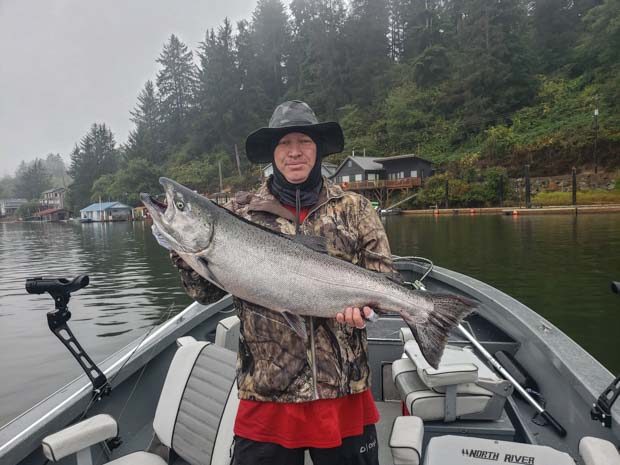 person standing in boat wearing a hat and holding large fish they just caught