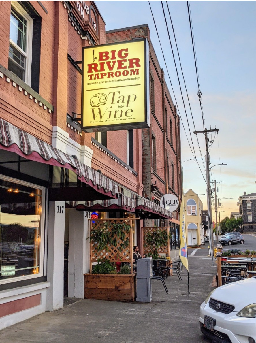 exterior of historic commercial building with lighted sign for Big River Taproom