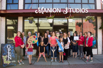 group poses in front of retail storefront with sign for Manion Studios on the awning of building
