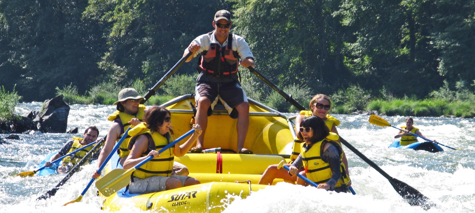 Rafters riding along the Rogue River in a yellow raft