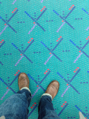 patterned carpet with feet and legs of photographer in frame