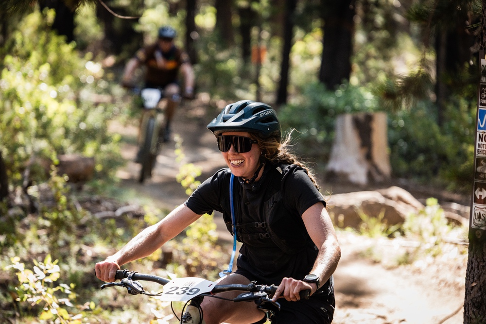 A smiling woman biking through mountain trails