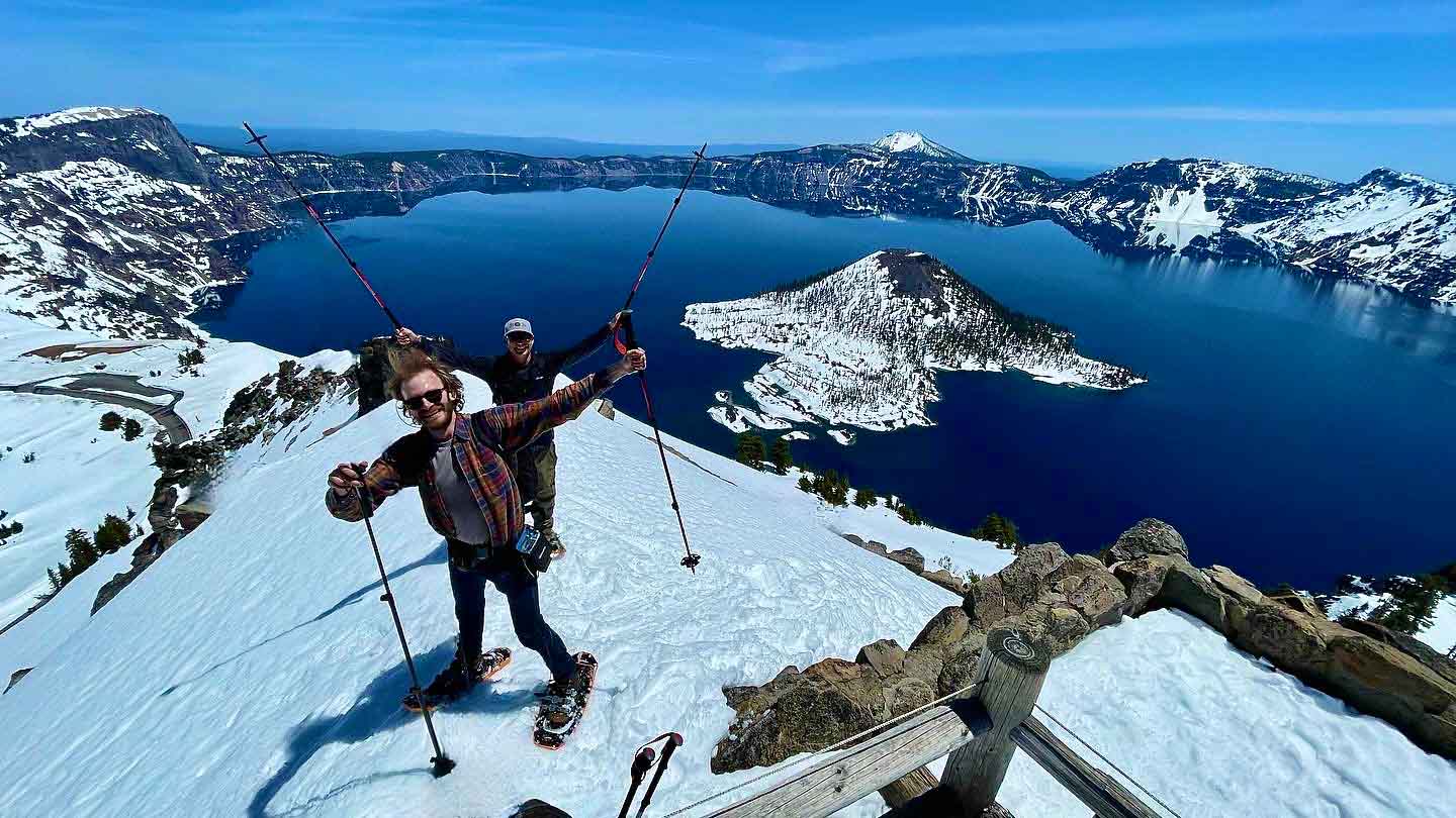 Two male snowshoers celebrate their trek at Crater Lake