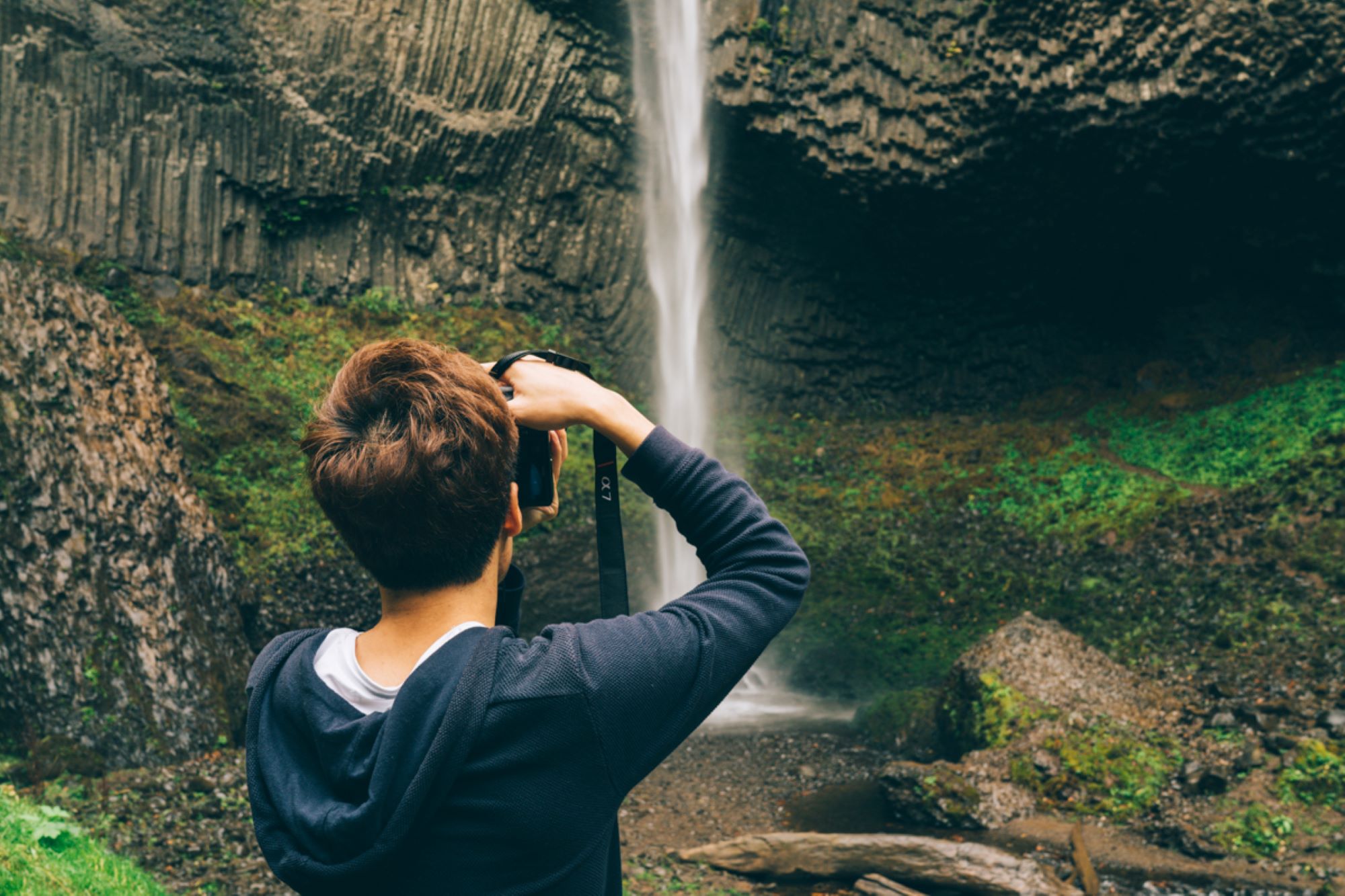 A woman takes a picture of a waterfall in the Gorge