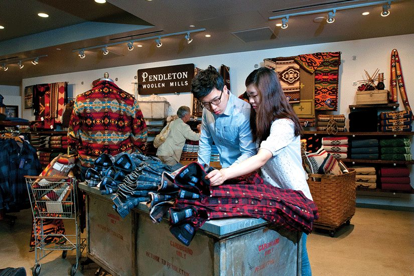 two people touch folder flannel shirts in retail display