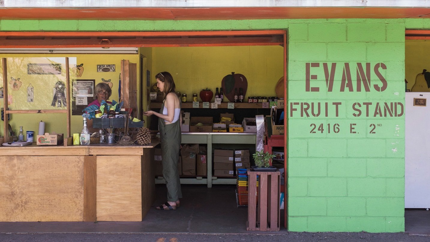 A woman purchasing fresh fruit from a farm stand