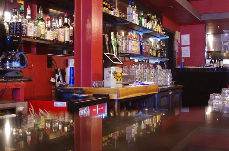 Bar with liquor bottles, glasses, and a coffee machine.