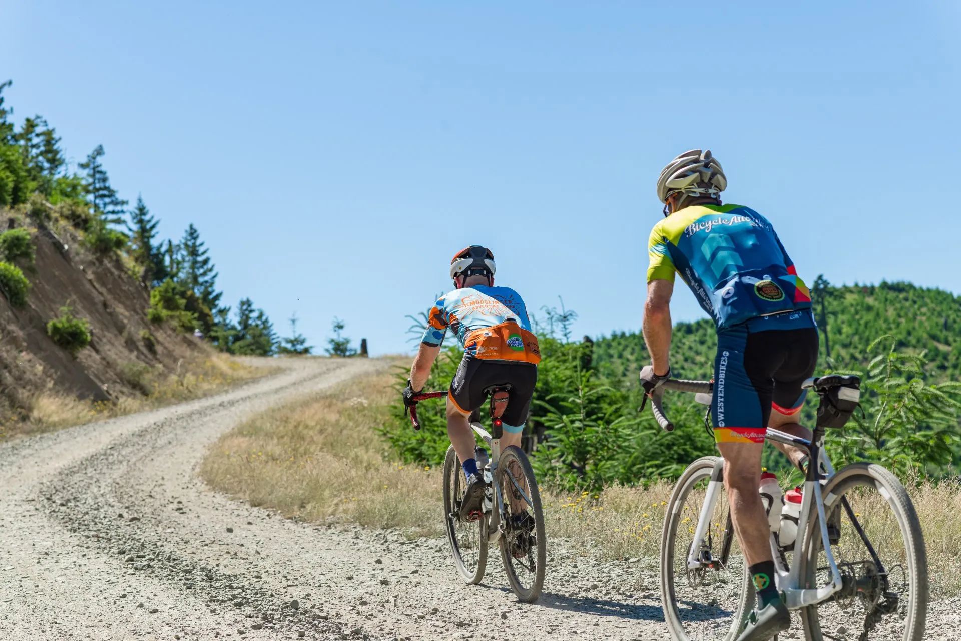 Two cyclists ride up a steep gravel trail.
