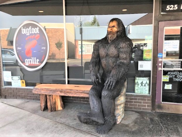 Carving of Bigfoot sitting on bench outside restaurant