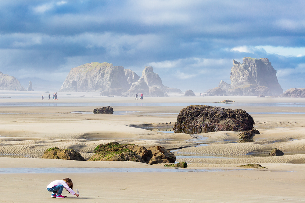 Kid playing on the beach at low tide in Bandon, Oregon