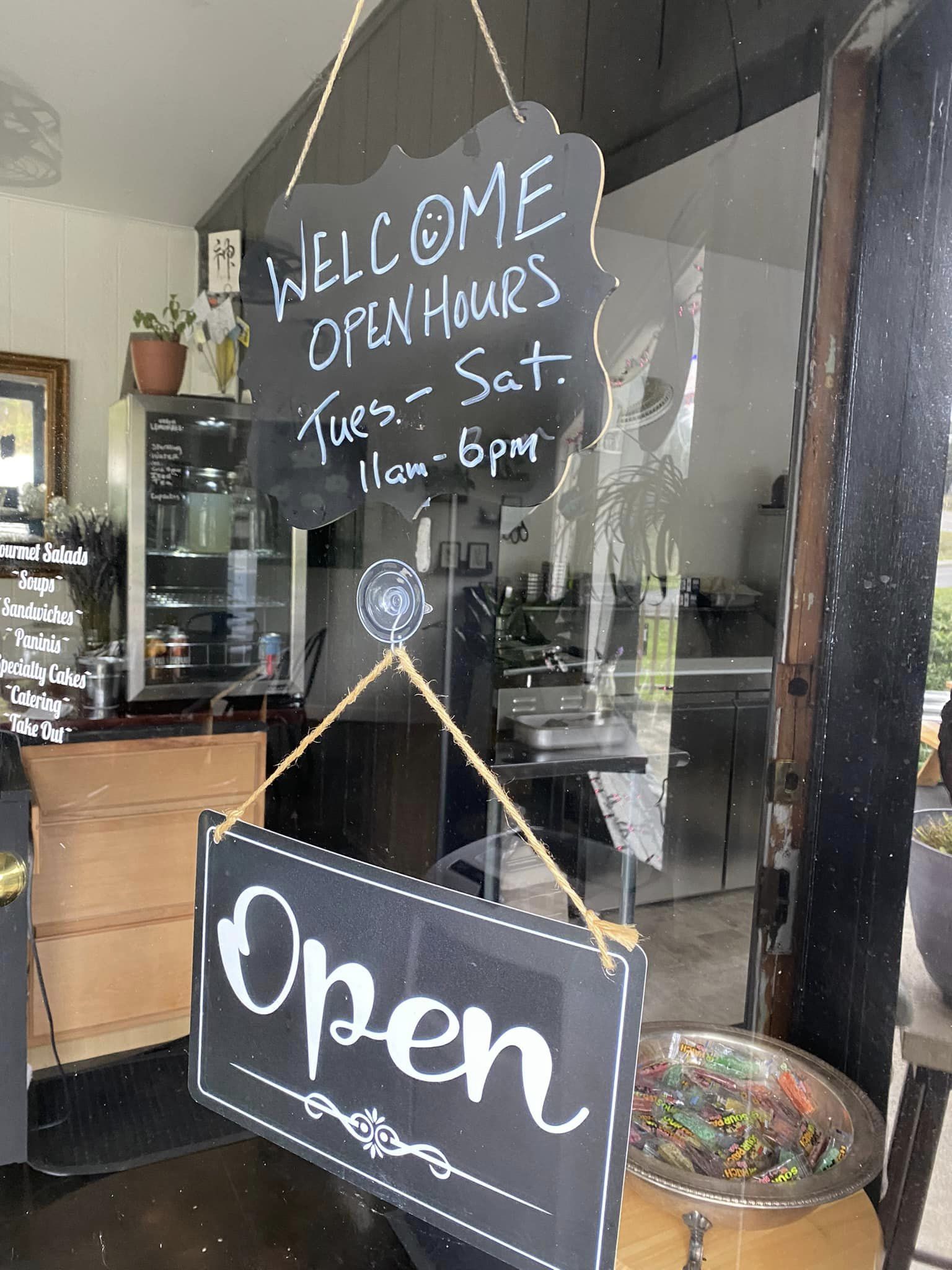 Welcome sign with hours of operation at Divine South Kitchen and Catering in Gold Beach, Oregon