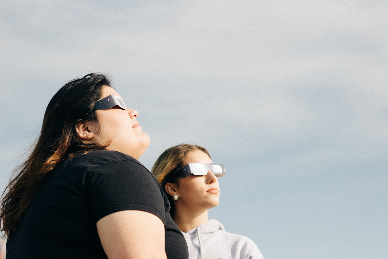 Two women wearing safety glasses during an eclipse